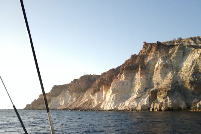 Santorini Catamaran Cruise with Fresh Meal and Open Bar - Cruising the coastline: lighthouse, Indian Rock, and the Black Mountain pass